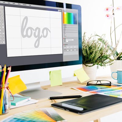 Logo design programs and illustration equipment open on desk