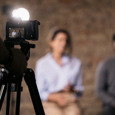 Two people preparing to be filmed with camera in foreground